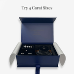 Open navy ring try-on kit box showing four carat-size stone replicas arranged in slots, along with adjustable try-on bands and a ring sizer, with the headline “Try 4 Carat Sizes.”