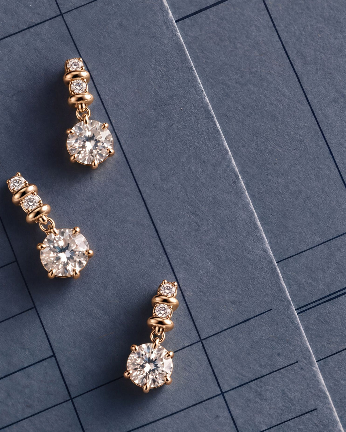 Three Sculpted Bail Round Pendants in yellow gold laid on navy record paper