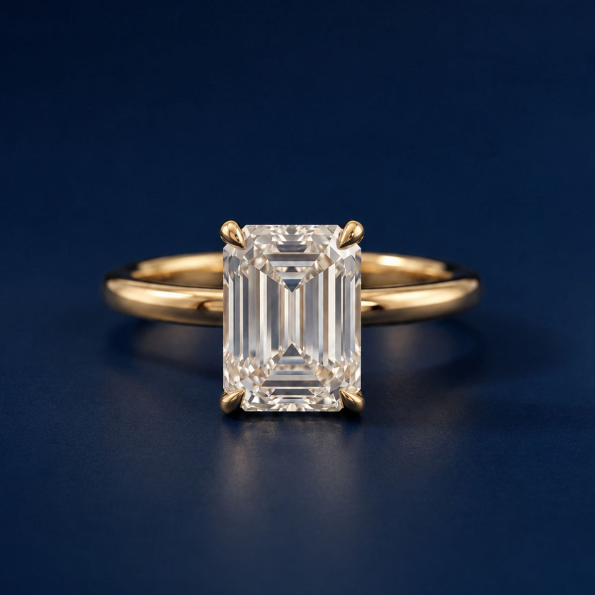 Emerald-cut diamond solitaire engagement ring on a yellow gold band, on navy