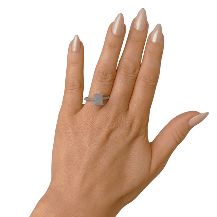 Emerald-cut printed stone placed on a hand to compare size before choosing a ring