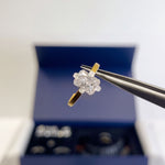 A radiant-shaped try-on stone held in tweezers above the open kit