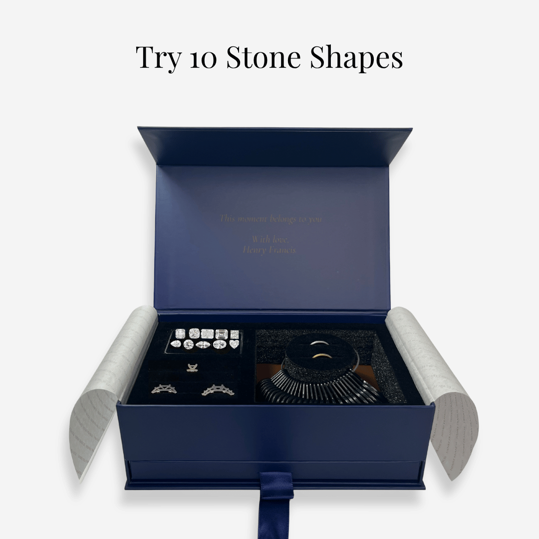 Open navy ring try-on kit box showing ten stone shape samples arranged in slots and a ring sizer with the headline "Try 10 stone shapes".
