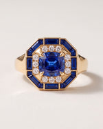 Octagon Sapphire Signet Ring in 18k yellow gold, a cushion blue sapphire in a halo of round diamonds inside an eight-sided frame of sapphire baguettes