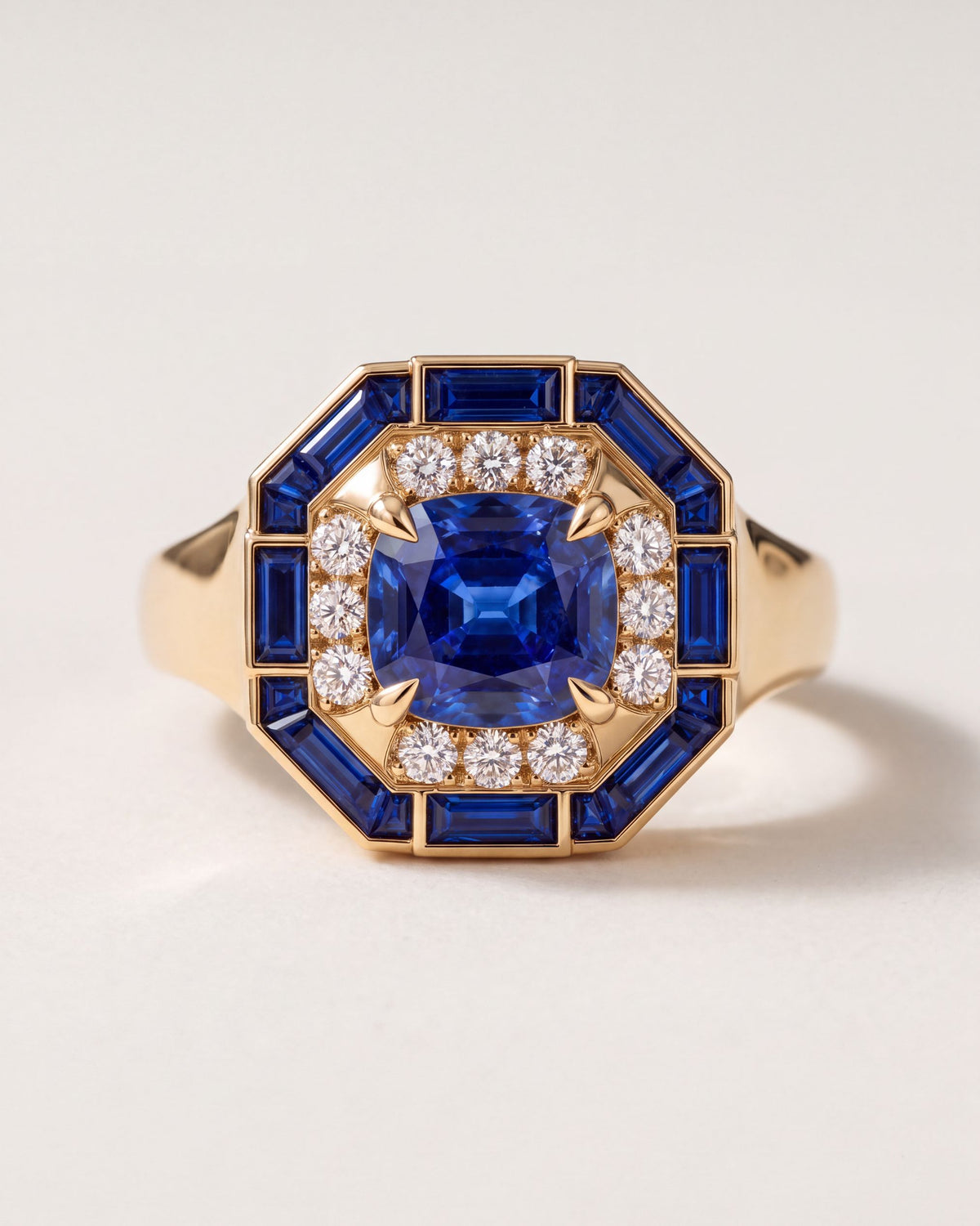 Octagon Sapphire Signet Ring in 18k yellow gold, a cushion blue sapphire in a halo of round diamonds inside an eight-sided frame of sapphire baguettes