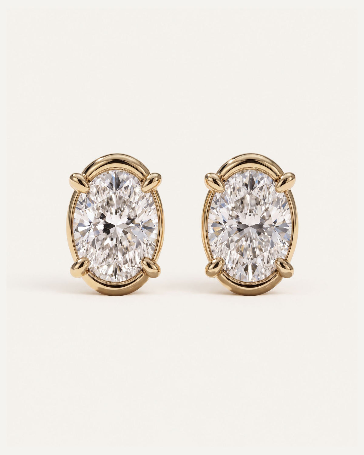 Signature Curved Diamond Studs, a pair of 1 carat oval diamonds in four claws with a curved 14k yellow gold surround