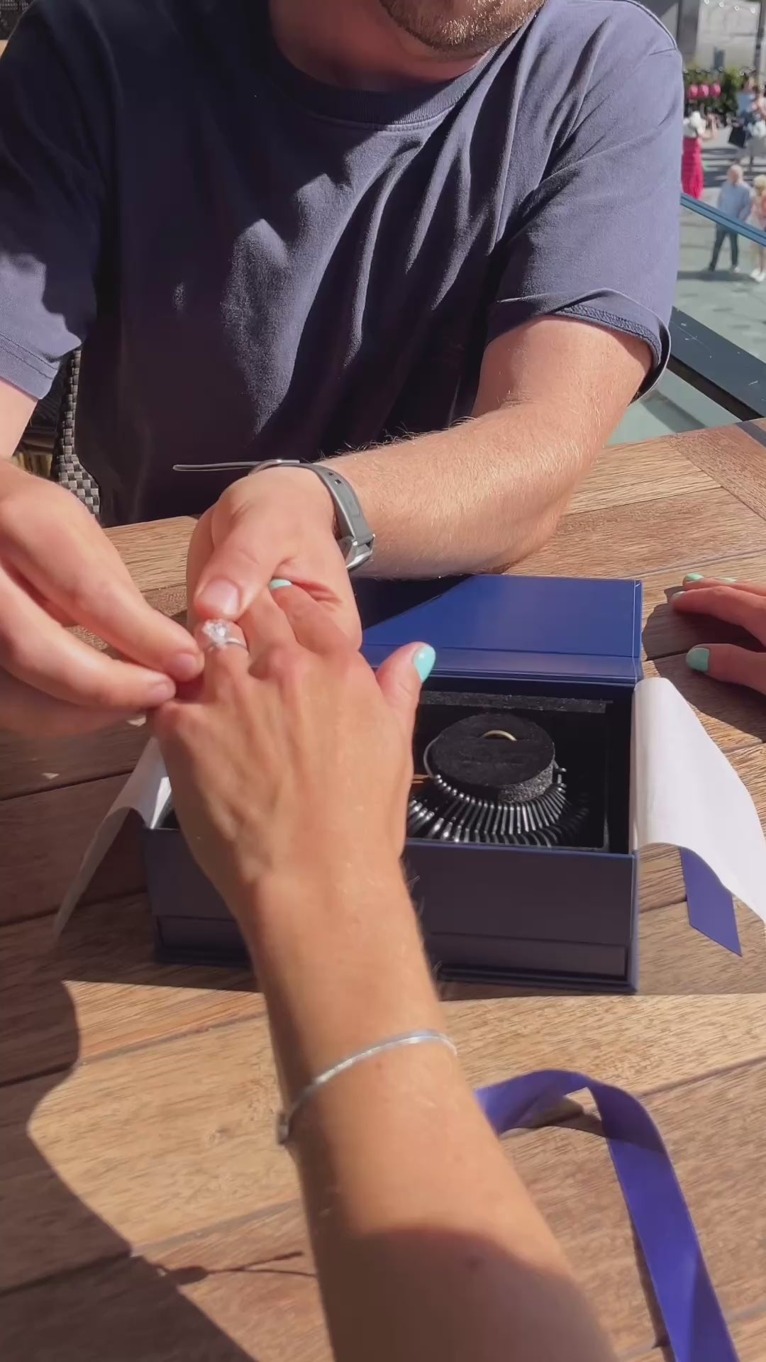 A couple trying the Ring Try-On Kit at an outdoor café table